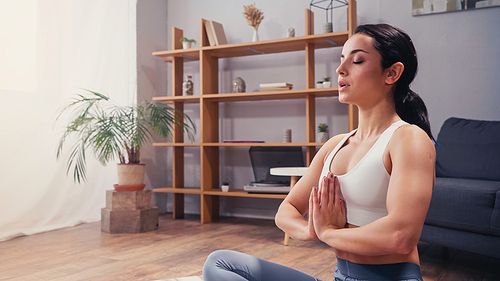 Sportswoman meditating with closed eye at home