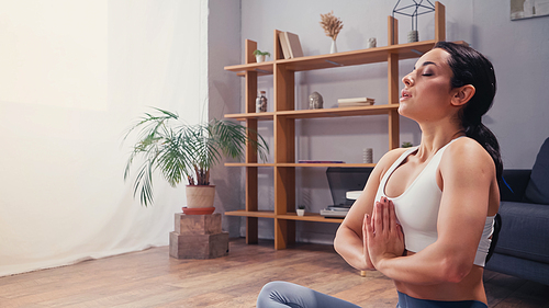 Side view of sportswoman meditating in living room