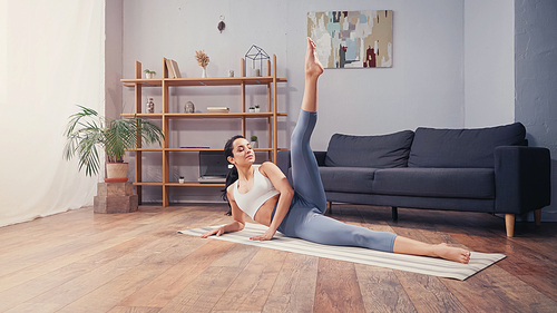 Athletic sportswoman training on fitness mat in living room