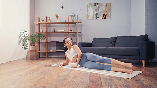 Pretty sportswoman working out on fitness mat at home