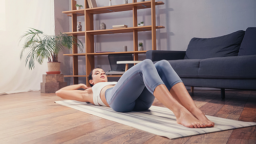 Sportswoman lying on fitness mat while training at home