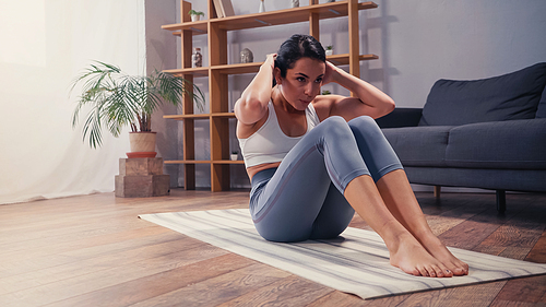 Sportswoman doing abs on fitness mat at home