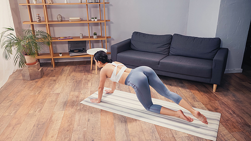 High angle view of fit sportswoman training on fitness mat at home