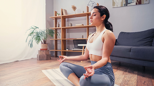 Pretty woman in sportswear meditating on yoga mat