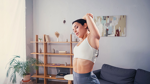Pretty fit woman stretching arms in living room