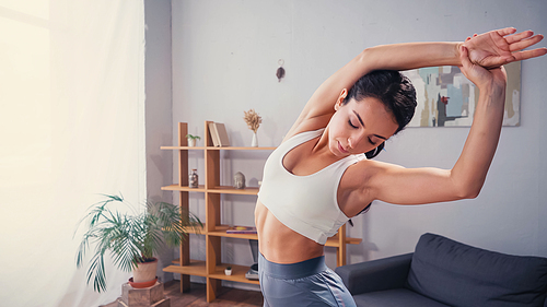 Young sportswoman warming up in living room