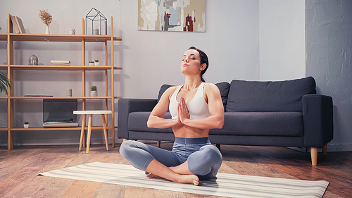 Barefoot sportswoman practicing yoga in living room