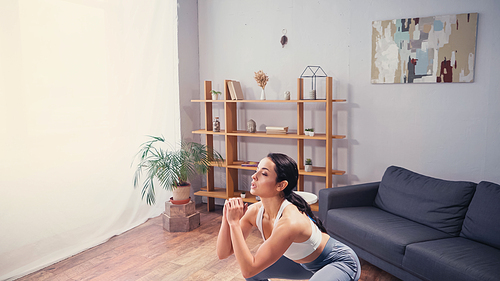 Pretty sportswoman doing squat at home