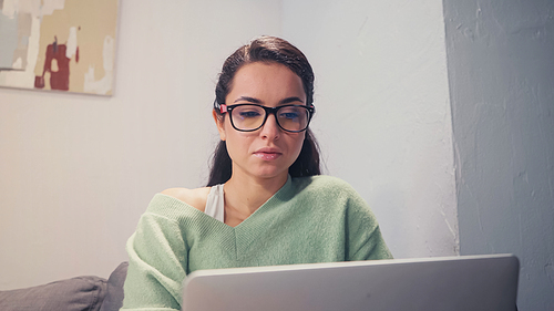 Freelancer working on blurred laptop at home