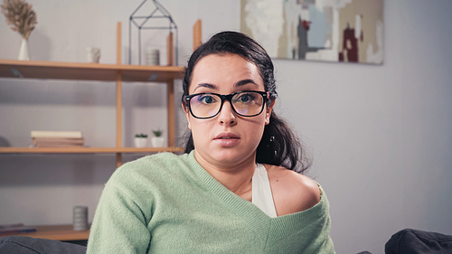Confused woman in eyeglasses  in living room
