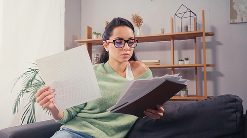 Student holding papers and folder at home