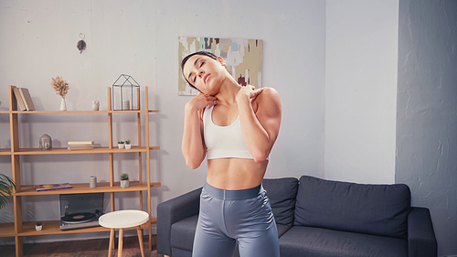 Pretty sportswoman with closed eyes stretching at home
