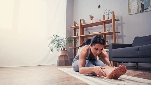 Focused sportswoman stretching at home