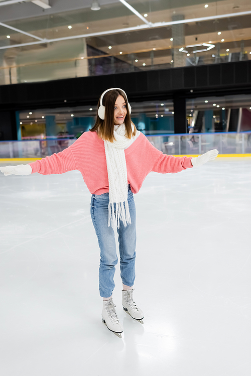 full length of astonished woman in winter outfit skating on ice rink