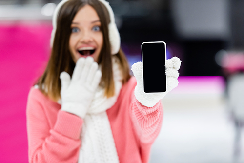 blurred and amazed woman in gloves holding smartphone with blank screen
