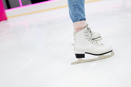cropped view of woman on white ice skates on frozen rink