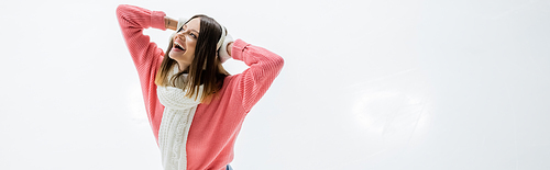 cheerful young woman adjusting ear muffs on ice rink, banner