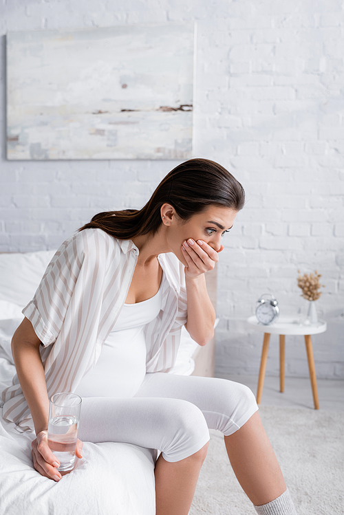 pregnant woman feeling nausea and covering mouth