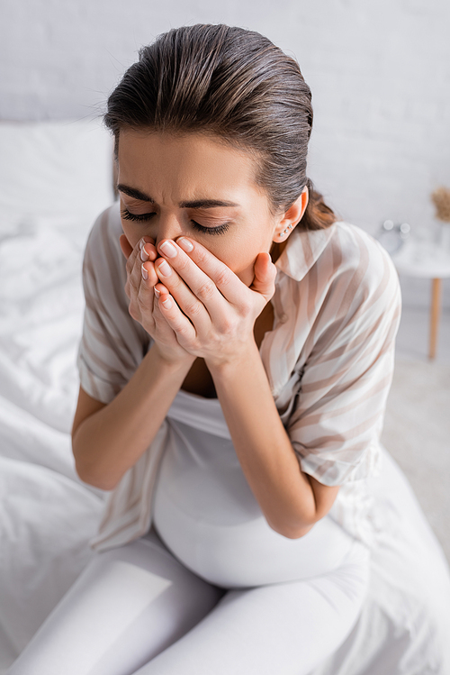 young pregnant woman feeling nausea and covering mouth