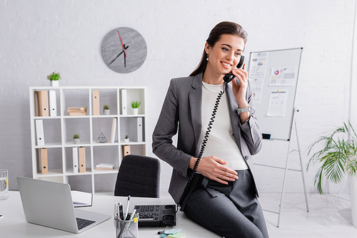 happy pregnant businesswoman talking on retro telephone
