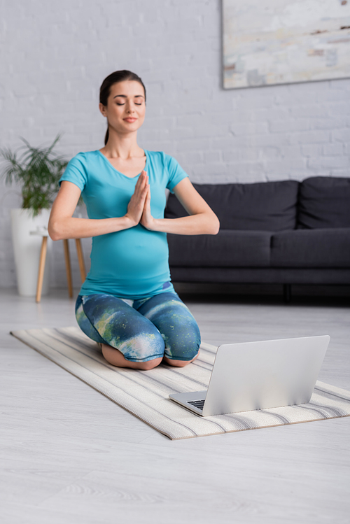 laptop on fitness man near blurred pregnant woman with praying hands