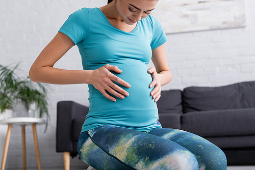 young pregnant woman in sportswear touching belly