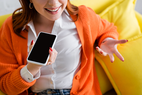 cropped view of smiling woman gesturing while sending voice message on mobile phone with blank screen
