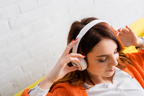 high angle view of pleased young woman with closed eyes listening music in headphones