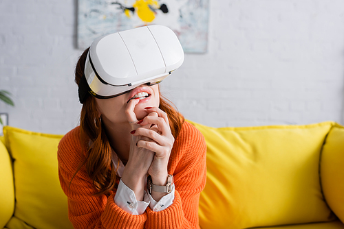 worried woman with clenched hands gaming in vr headset at home