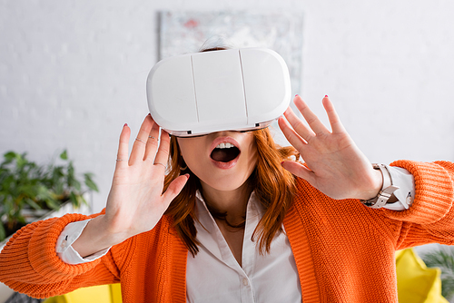amazed woman with open mouth gesturing while gaming in vr headset at home