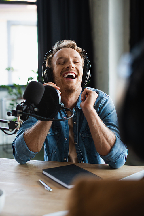 joyful radio host laughing near microphone in studio
