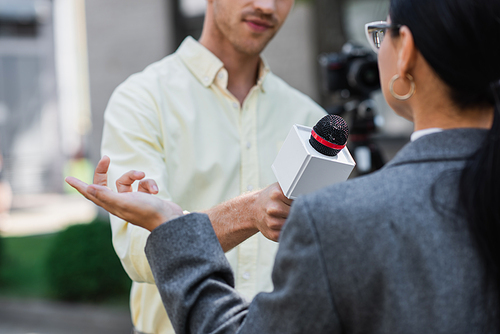 blurred reporter holding microphone near blurred businesswoman