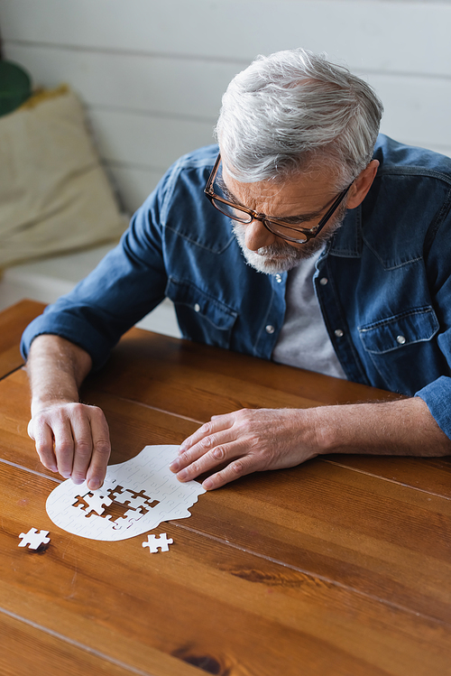 Senior man with dementia holding puzzle on table