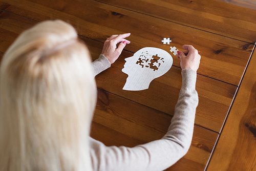 Overhead view of senior woman with dementia folding jigsaw