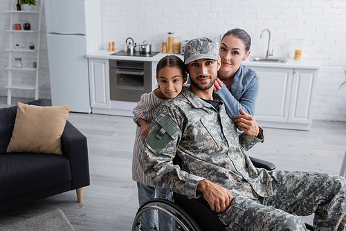 Man in military uniform and wheelchair  near family at home