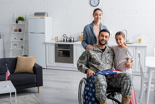 Family  near father in military uniform and wheelchair with american flag at home