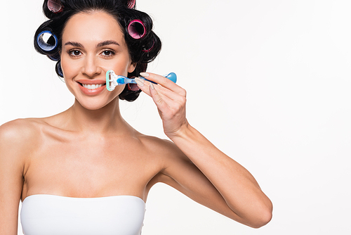 positive young woman in curlers and bra holding razor near face isolated on white