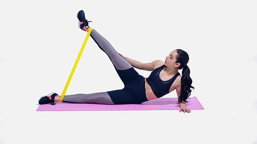 brunette young sportswoman working out with yellow elastics on fitness mat on white