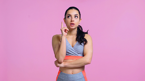 surprised young woman in sportswear pointing with finger isolated on pink