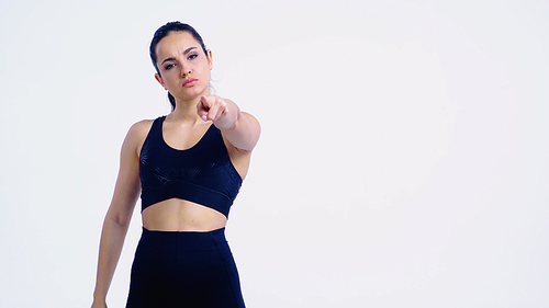 displeased young woman in sportswear pointing with finger and  isolated on white