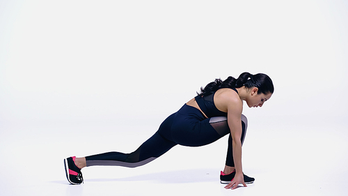 flexible young woman in sportswear stretching on white