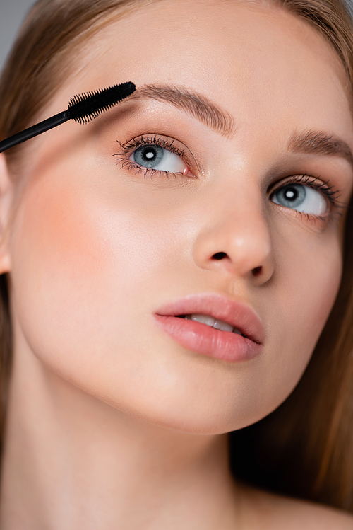 close up of young woman applying mascara