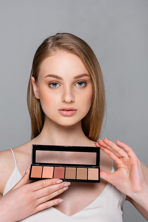 pretty woman holding cosmetic blush palette isolated on grey