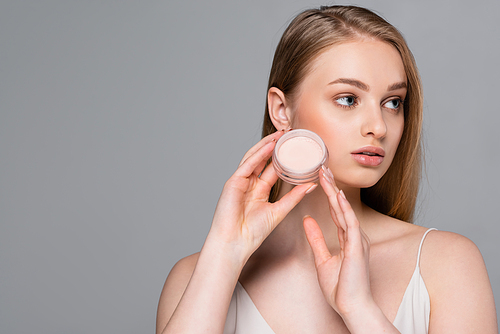 young woman holding face powder container isolated on grey