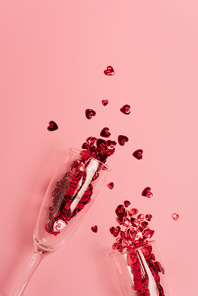 top view of champagne glasses with confetti hearts on pink