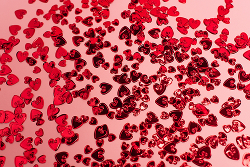 top view of shiny red confetti hearts on pink
