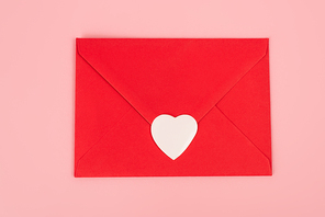 top view of paper heart sticker on red envelope isolated on pink