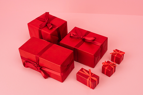red wrapped gift boxes with ribbons on pink