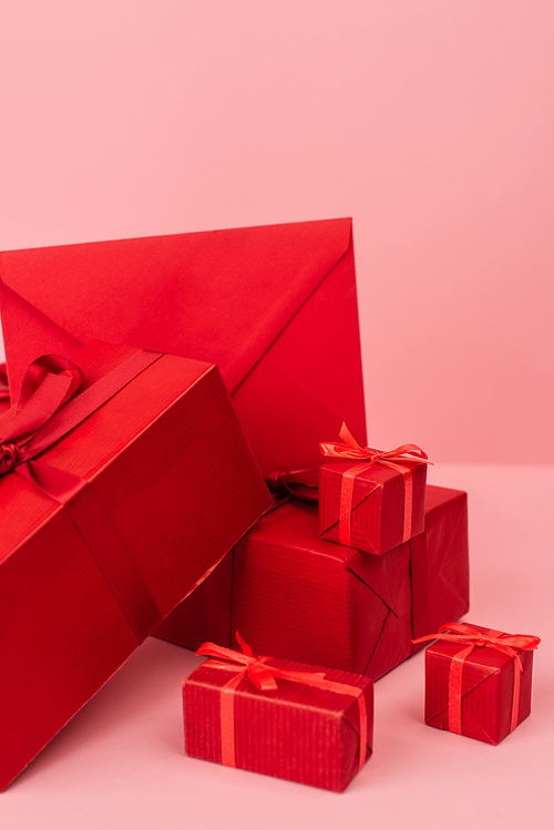 red wrapped gift boxes and envelope on pink