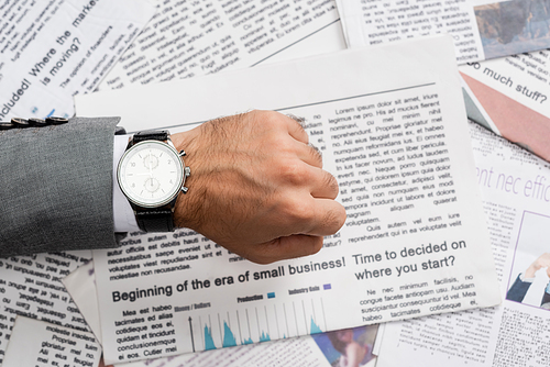 top view of businessman showing wristwatch above newspaper